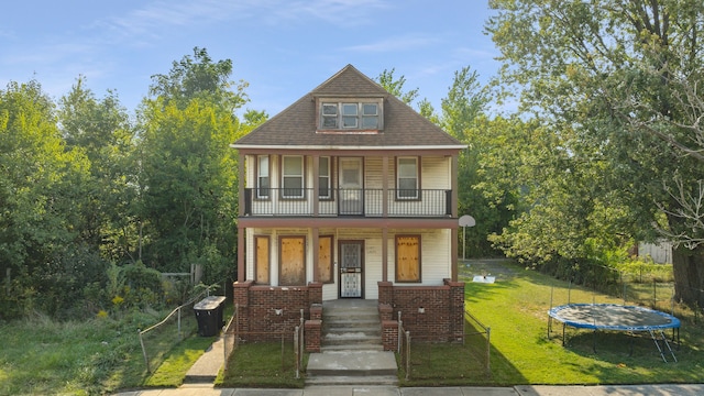 view of front of home featuring a porch, a front yard, and a trampoline