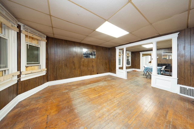 basement featuring hardwood / wood-style floors, a paneled ceiling, and wooden walls