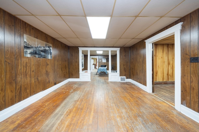 basement with a paneled ceiling, wood walls, and hardwood / wood-style flooring