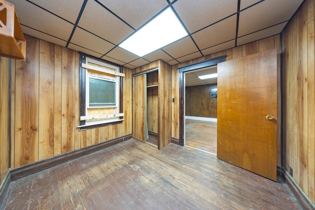 spare room with hardwood / wood-style flooring, a paneled ceiling, and wooden walls