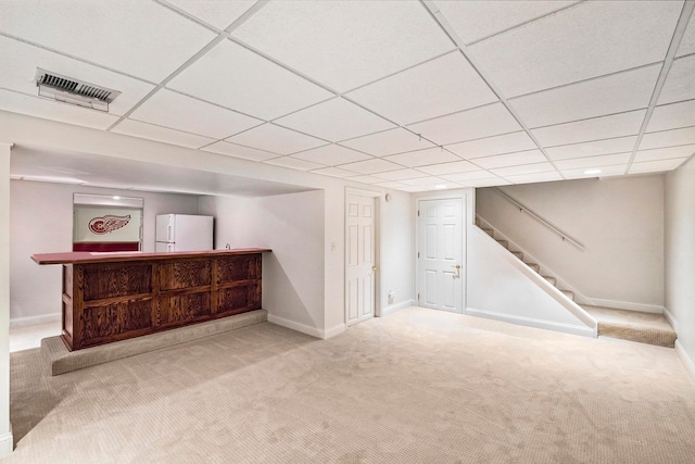 basement featuring light colored carpet, a drop ceiling, and white fridge