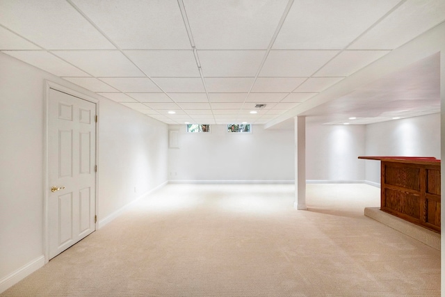 basement featuring a paneled ceiling and light colored carpet