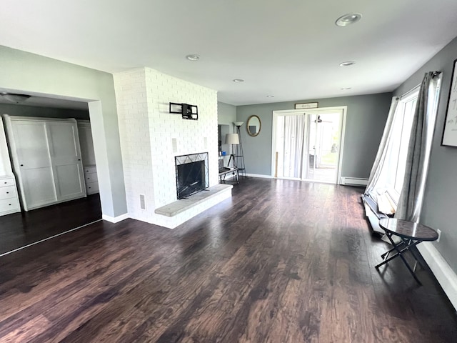 unfurnished living room with dark hardwood / wood-style flooring, a baseboard radiator, and a brick fireplace