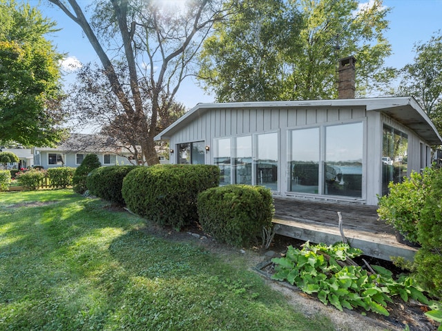 view of side of property with a sunroom and a lawn