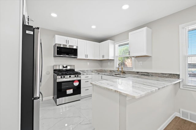 kitchen featuring white cabinets, kitchen peninsula, sink, and appliances with stainless steel finishes