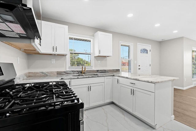 kitchen with white cabinetry, sink, light stone counters, gas range oven, and kitchen peninsula