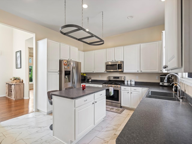 kitchen with a center island, sink, light wood-type flooring, appliances with stainless steel finishes, and white cabinetry