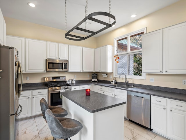 kitchen with white cabinetry, sink, stainless steel appliances, a kitchen breakfast bar, and a kitchen island