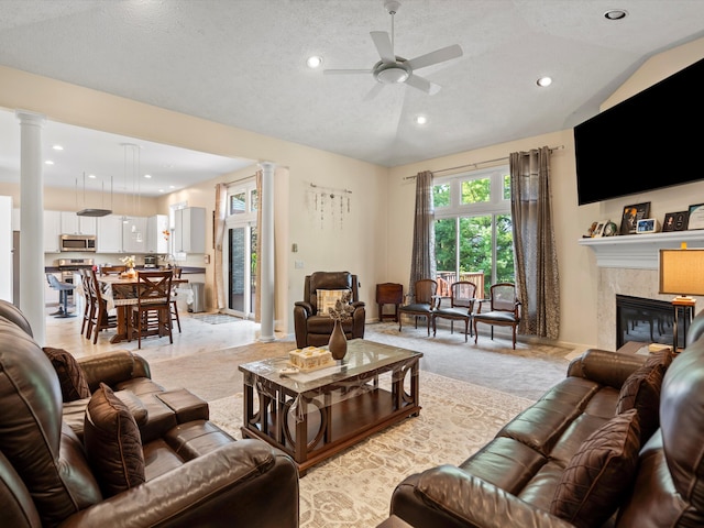 carpeted living room with ornate columns, ceiling fan, a textured ceiling, lofted ceiling, and a fireplace