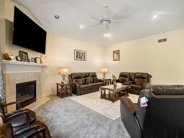 living room with ceiling fan, lofted ceiling, and a tiled fireplace