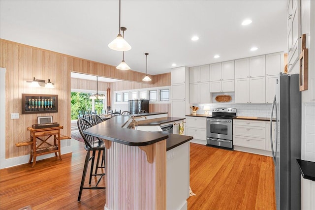 876 S Beach, Pentwater, MI 49449 - kitchen with appliances with stainless steel finishes, dark countertops, a kitchen bar, light wood-style flooring, and backsplash
