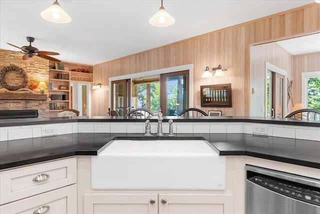 876 S Beach, Pentwater, MI 49449 - kitchen featuring dishwasher, a sink, wooden walls, a ceiling fan, and white cabinetry
