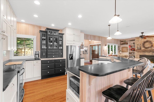 876 S Beach, Pentwater, MI 49449 - kitchen with appliances with stainless steel finishes, dark countertops, a breakfast bar, wood walls, and glass insert cabinets