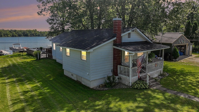 76 Sundago Park St, Hastings, MI 49058 - back of house at dusk with a porch, a chimney, a water view, a yard, and metal roof