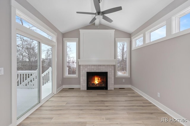 unfurnished living room featuring a tile fireplace, ceiling fan, light hardwood / wood-style floors, and lofted ceiling