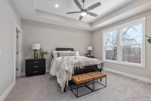 carpeted bedroom featuring ceiling fan and a tray ceiling