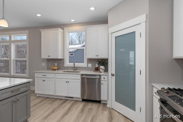 kitchen with appliances with stainless steel finishes, decorative light fixtures, white cabinetry, and sink