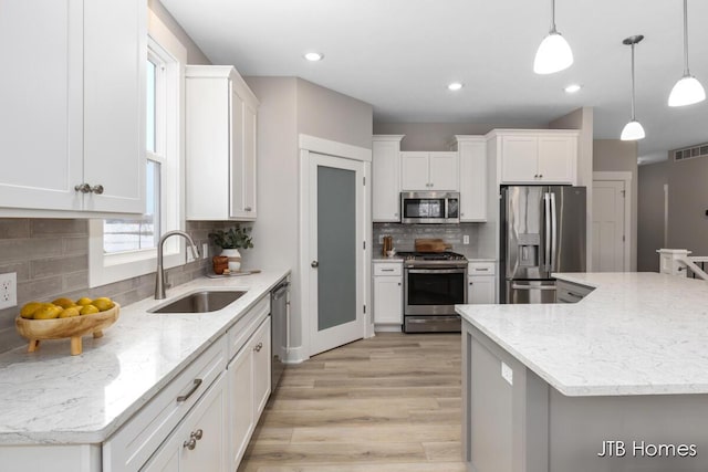 kitchen featuring pendant lighting, a kitchen island, white cabinets, and stainless steel appliances