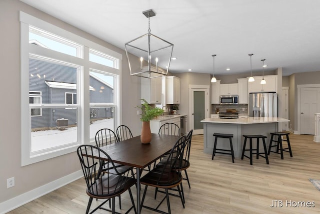 dining room with sink, an inviting chandelier, and light wood-type flooring