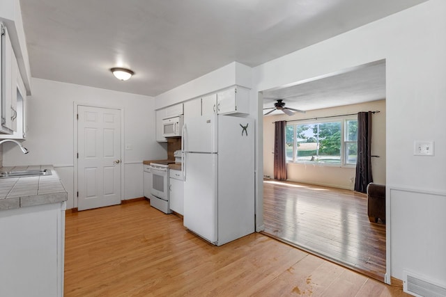 kitchen featuring white appliances, white cabinets, sink, ceiling fan, and light wood-type flooring