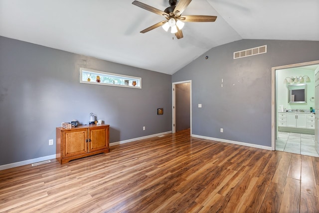 unfurnished bedroom with ceiling fan, light hardwood / wood-style floors, lofted ceiling, and ensuite bathroom