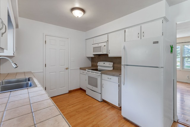 kitchen featuring sink, tile countertops, white appliances, white cabinets, and light wood-type flooring