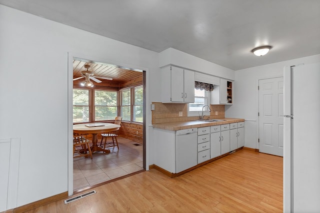 kitchen with light hardwood / wood-style floors, white cabinetry, white appliances, and a healthy amount of sunlight