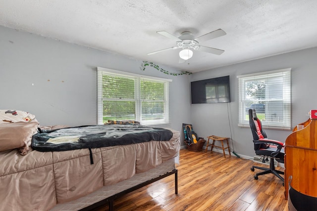 bedroom featuring hardwood / wood-style floors, a textured ceiling, and ceiling fan