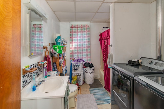 full bathroom featuring a drop ceiling, washer and clothes dryer, toilet, shower / bath combo with shower curtain, and vanity