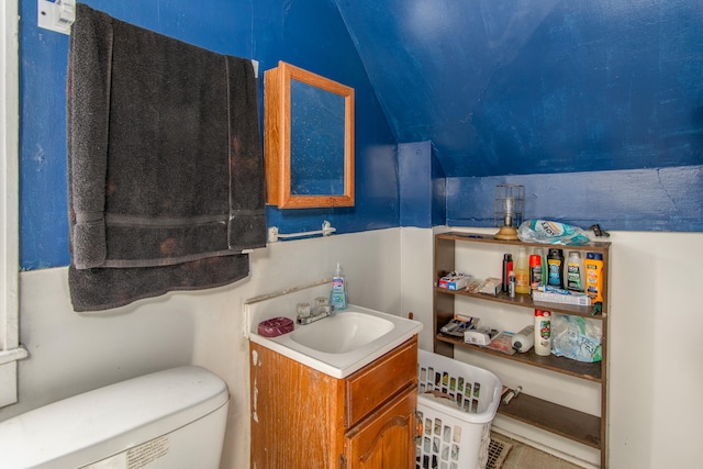 bathroom featuring vanity, toilet, and lofted ceiling