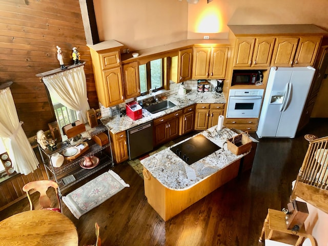 kitchen featuring a healthy amount of sunlight, light stone countertops, black appliances, and wood walls