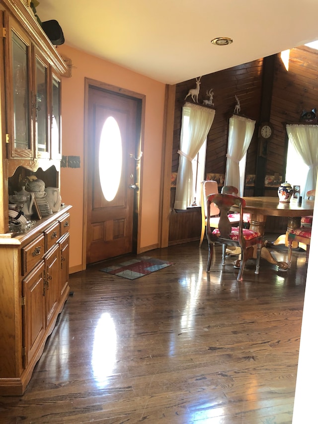 foyer with dark wood-type flooring and wooden walls