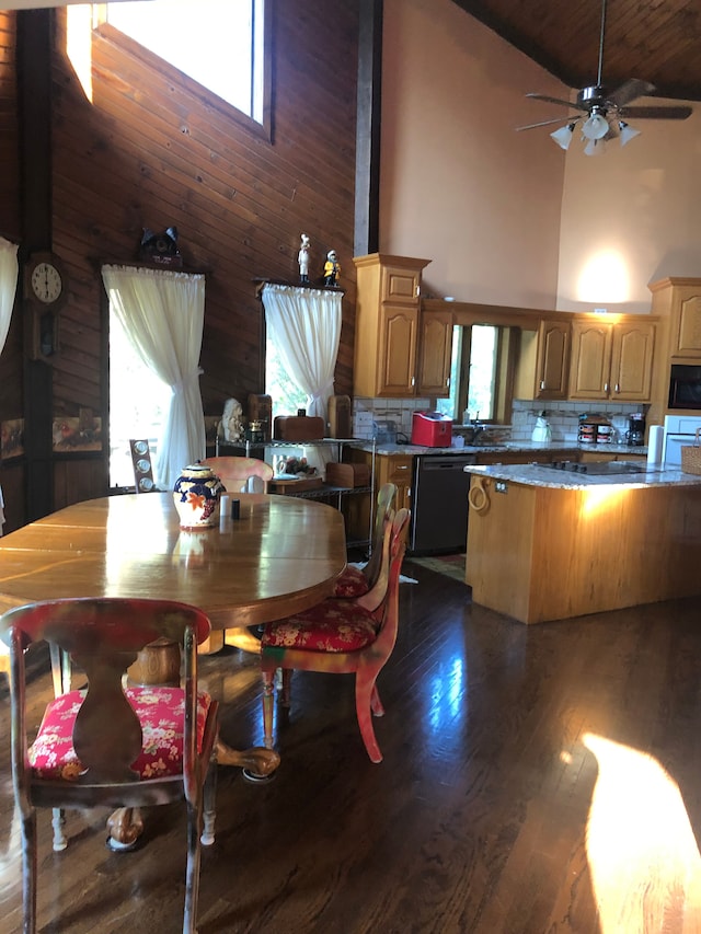 dining area featuring wooden walls, plenty of natural light, high vaulted ceiling, and dark hardwood / wood-style floors