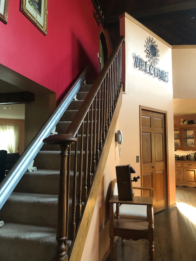 staircase featuring wood-type flooring and a high ceiling