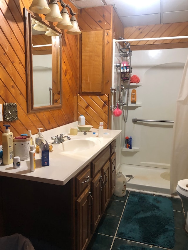 bathroom featuring vanity, a shower with curtain, wooden walls, tile patterned flooring, and toilet