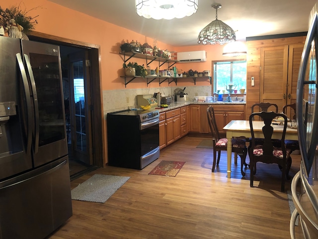 kitchen with a wall mounted air conditioner, hanging light fixtures, sink, appliances with stainless steel finishes, and wood-type flooring