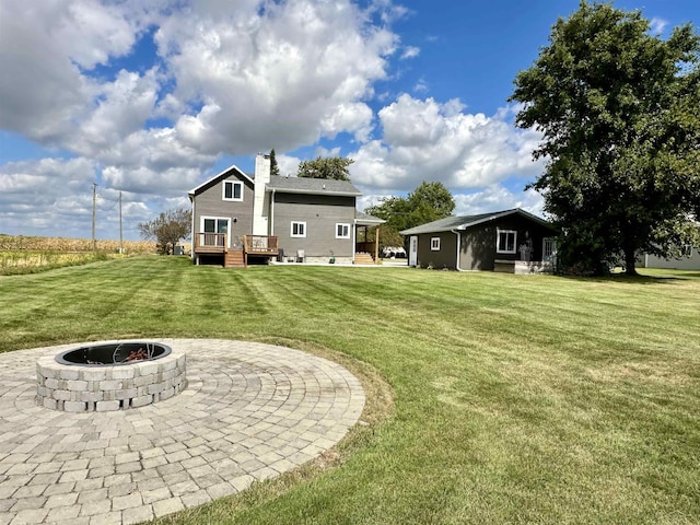 view of yard with a fire pit, an outdoor structure, a patio area, and a deck