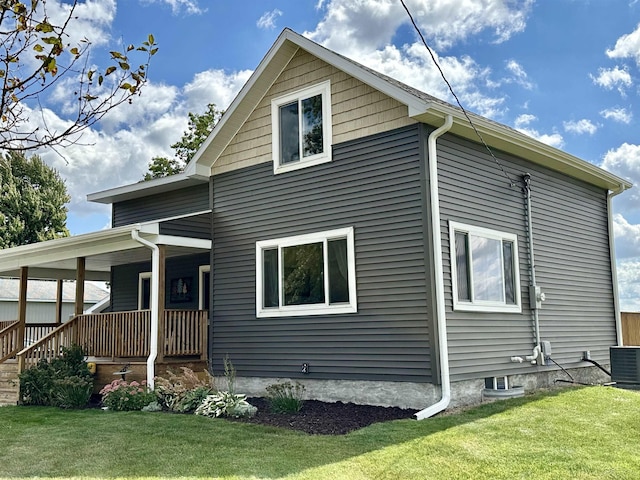 exterior space with covered porch, cooling unit, and a lawn