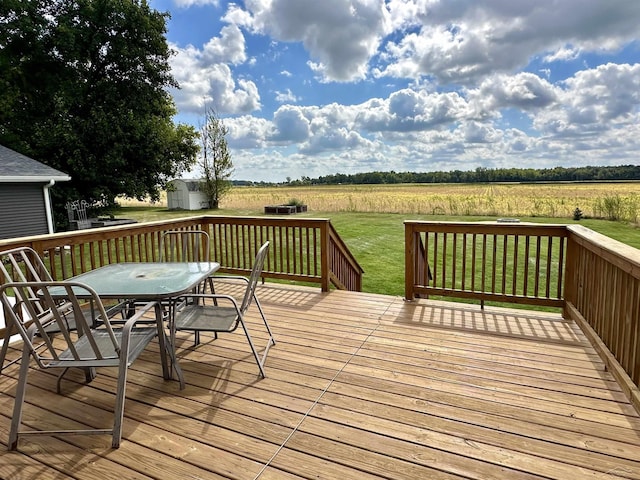 deck featuring a lawn, a rural view, and a shed