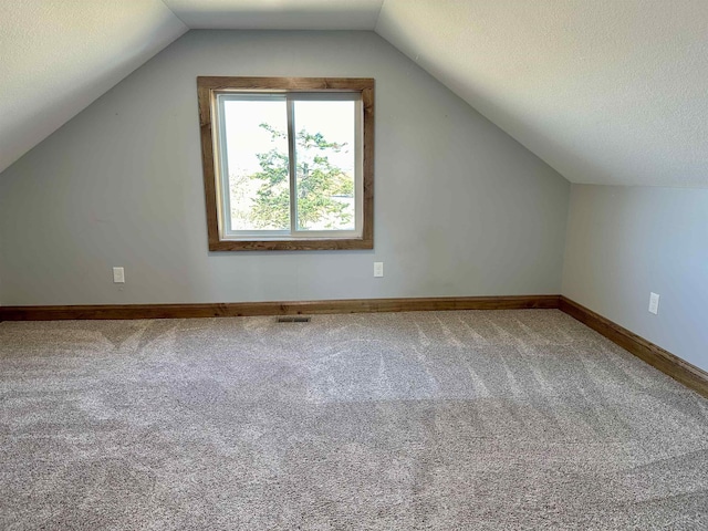 bonus room with a textured ceiling, lofted ceiling, and carpet floors