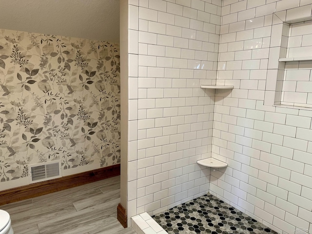 bathroom featuring tiled shower and wood-type flooring