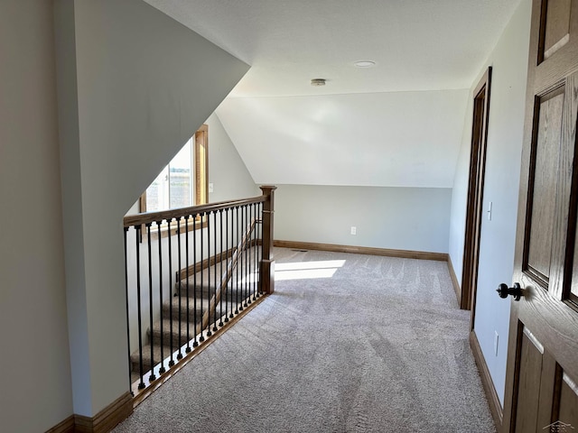 corridor with light carpet and vaulted ceiling