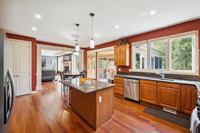 kitchen featuring appliances with stainless steel finishes, light wood-type flooring, a kitchen island, and plenty of natural light