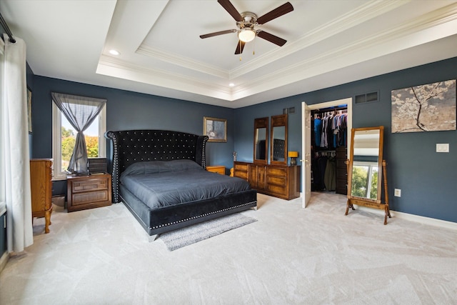 carpeted bedroom featuring a raised ceiling, crown molding, ceiling fan, a spacious closet, and a closet