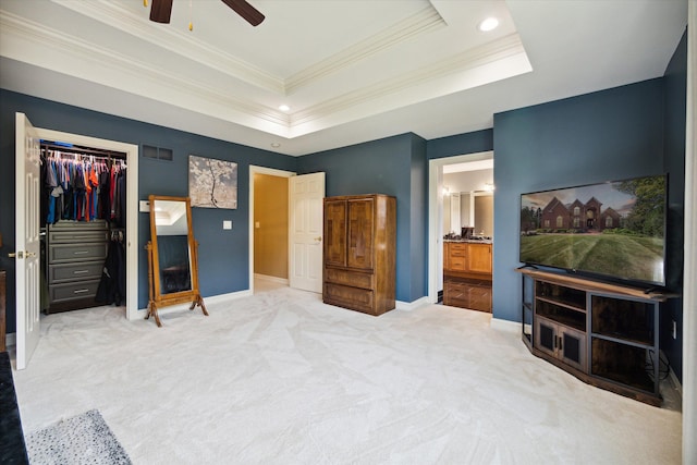 carpeted bedroom with connected bathroom, ceiling fan, a tray ceiling, a closet, and ornamental molding