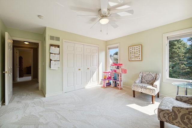 sitting room with ceiling fan and light colored carpet