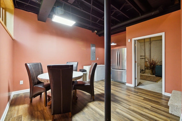 dining space with hardwood / wood-style flooring, a towering ceiling, and electric panel