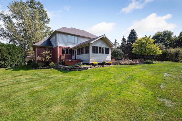 back of property featuring a sunroom, a yard, and a hot tub