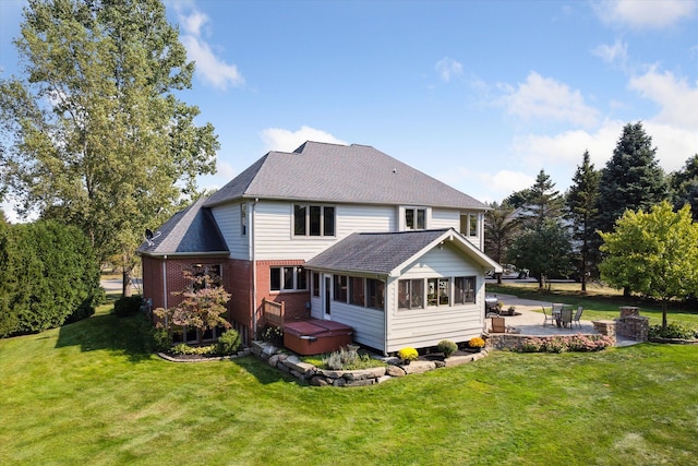 rear view of house with a sunroom, a yard, a patio, and a hot tub