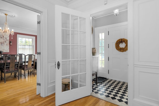 entrance foyer featuring a notable chandelier, light wood-type flooring, and ornamental molding